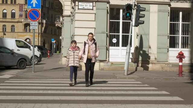 Lady with child on pedestrian crossing in town. rA view of esponsible mother with littel girl walk on pedestrian crossing in the big city.