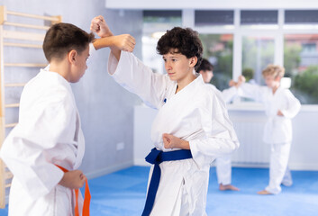 Diligent preteen karate students practicing fighting techniques during workout session