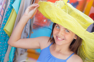 Cute Blue Eyed Girl Playfully Modeling a Big Sun Hat at the Market.