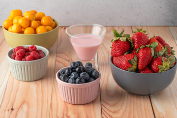 Wooden table with bowls with fruit and yogurt