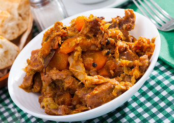 Appetizing cabbage stewed with pork meat and carrots on white plate..