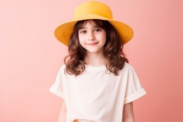 Portrait of a cute little girl in a yellow hat on a pink background