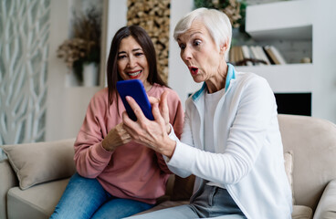 Shocked elderly multiracial women watching video on smartphone