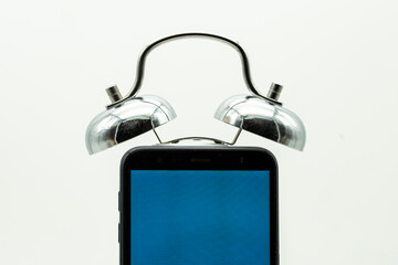 Teléfono móvil con unas campanas de un reloj despertador, aislado en blanco
