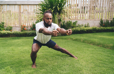 Young African American man exercising on meadow in garden