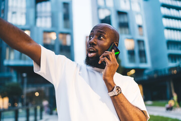 Amazed black man having phone call on street
