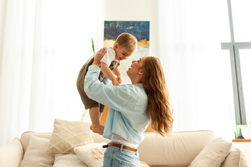 mother plays and rejoices with her little son at home, a young woman lifts her child up and laughs...