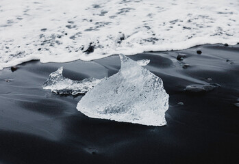 This black sand beach is formed from a volcanic rocks and sand filled with crystal clear icebergs that are washed up from the sea. Diamond beach in Jökulsárlón, Iceland.