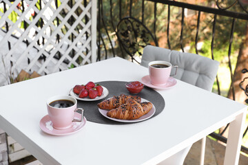 Outdoor breakfast with tea and croissants on white table on terrace