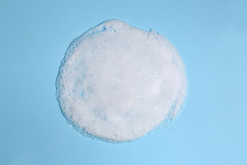 Foaming cleanser on light blue background, above view. Skin care cosmetic