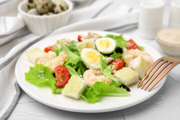 Delicious Caesar salad with shrimps and fork served on white table, closeup