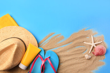 Flat lay composition with beach accessories and sand on light blue background, space for text