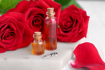 Bottles of love potion, red rose flowers and small key on table, closeup