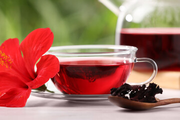 Delicious hibiscus tea and flowers on white wooden table, closeup