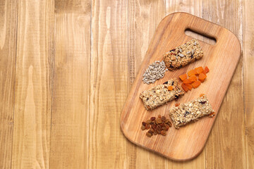 Different tasty granola bars and ingredients on wooden table, top view. Space for text