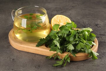 Aromatic tea, fresh parsley and lemon on grey table, closeup