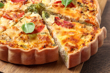 Tasty quiche with tomatoes, basil and cheese on wooden table, closeup