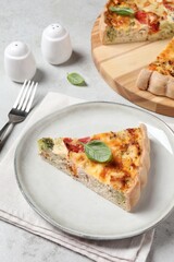 Tasty quiche with chicken, vegetables, basil and cheese served on light table