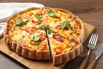 Tasty quiche with tomatoes, basil and cheese on wooden table, closeup