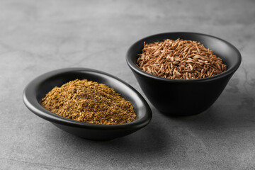 Caraway (Persian cumin) powder and dry seeds on gray table