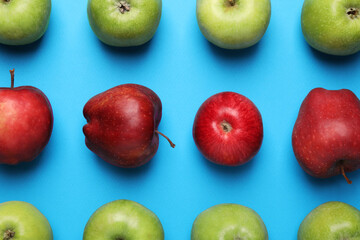 Ripe red and green apples on light blue background, flat lay