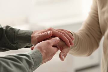 Trust and support. Men joining hands on blurred background, closeup