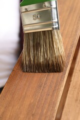 Applying wood stain onto wooden surface, closeup view
