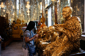 Thai travelers women people travel visit and respect praying blessing and cover thin gold leaf on...