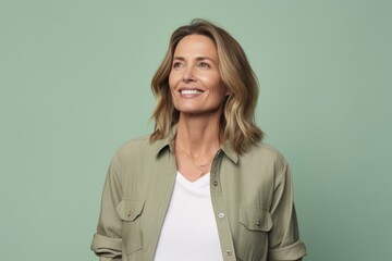 Cheerful mature woman looking at camera and smiling while standing against green background