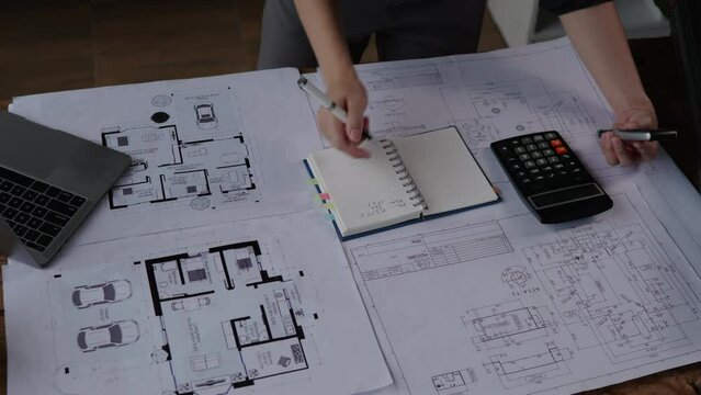 Engineer or architect working and calculations on paperworks blueprints construction drawings for structure for interior for houses and buildings.