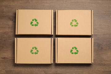 Cardboard boxes with recycle sign stamps on wooden background, flat lay