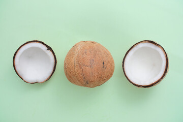 Three coconut halves arranged in a horizontal row on a pastel background. Creative space for product advertising with a top-down perspective. Tropical fruit theme.