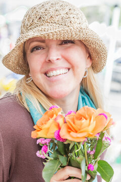 Smliing Blonde Woman Wearing a Hat Holding a Fresh Cut Floral Bouquet at the Farmers Market.