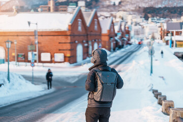 Man tourist Visiting in Hakodate, Traveler in Sweater sightseeing Kanemori Red Brick Warehouse with Snow in winter. landmark and popular for attractions in Hokkaido, Japan.Travel and Vacation concept