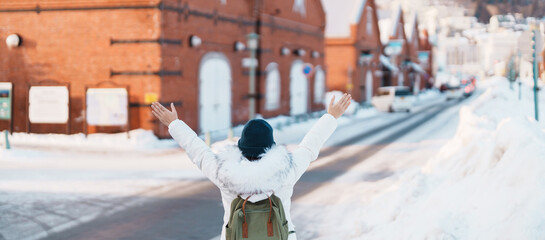 Woman tourist Visiting in Hakodate, Traveler in Sweater sightseeing Kanemori Red Brick Warehouse with Snow in winter. landmark and popular for attractions in Hokkaido,Japan.Travel and Vacation concept - obrazy, fototapety, plakaty