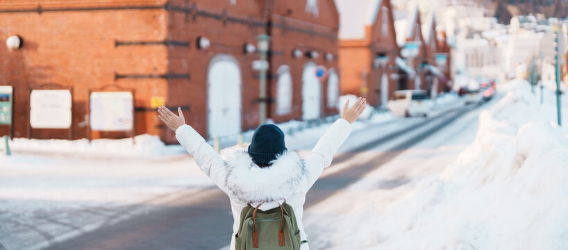 Woman tourist Visiting in Hakodate, Traveler in Sweater sightseeing Kanemori Red Brick Warehouse with Snow in winter. landmark and popular for attractions in Hokkaido,Japan.Travel and Vacation concept