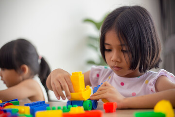 Adorable little girl playing toy blocks in a bright room