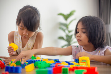 Adorable little girl playing toy blocks in a bright room