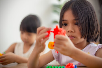 Adorable little girl playing toy blocks in a bright room