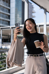 A cheerful Asian businesswoman is enjoying talking on a video call while walking in the city.