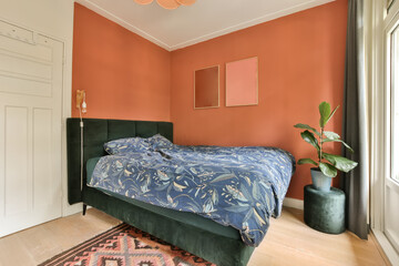 a bedroom with an orange wall and green headboard on the bed in the room is decorated with colorful...