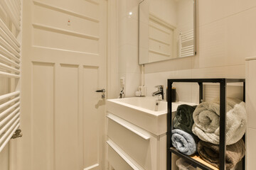 a bathroom with white walls and wood flooring, there is a towel rack on the wall next to the sink