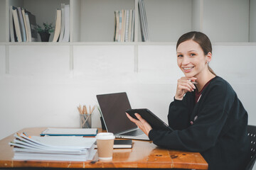 Female business woman using tablet and laptop for analyzing the business report in the office