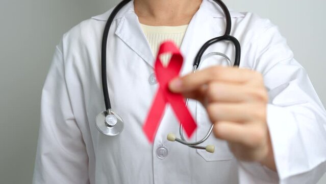 Doctor with Red Ribbon for December World Aids Day, acquired immune deficiency syndrome, multiple myeloma Cancer Awareness month and National Red ribbon week. Healthcare and world cancer day concept