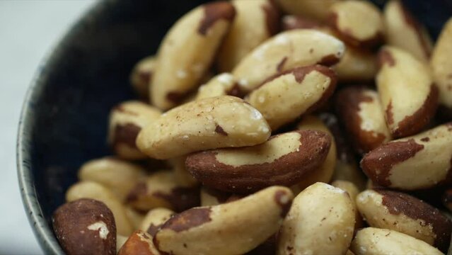 Brazil nuts rotating in blue bowl. Wholefood Brazil nut image of raw foods. Shallow depth of field HD footage of healthy plant-based food.