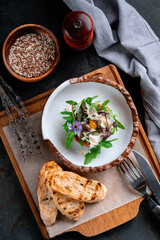 Beef tartare with chopped meat and decorated with arugula leaves and parmesan. Round-shaped raw beef dish