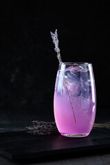 Pink spritz cocktail. Summer refreshing pink cocktail with lavender fragrance and ice in a glass glass on a dark background