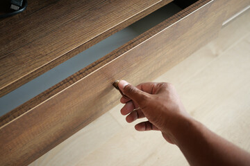 man's hand open drawer wooden in cabinet