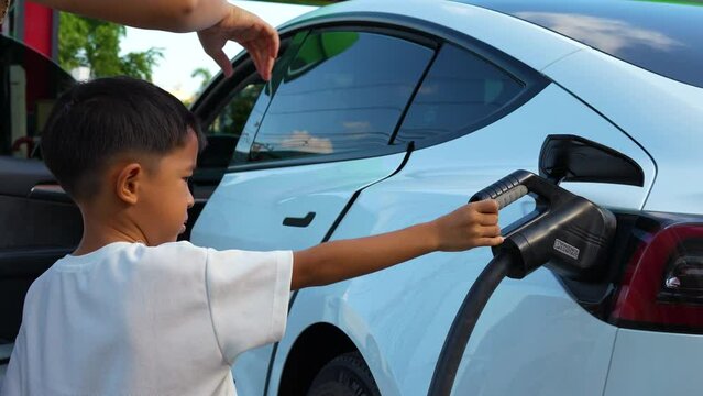 Adorable Asian Child Boy Using Electric Car Charge In Ev Station