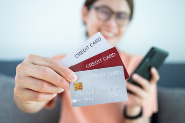 Asian woman showing her credit cards. A credit card is a type of credit facility, provided by banks that allow customers to borrow funds.